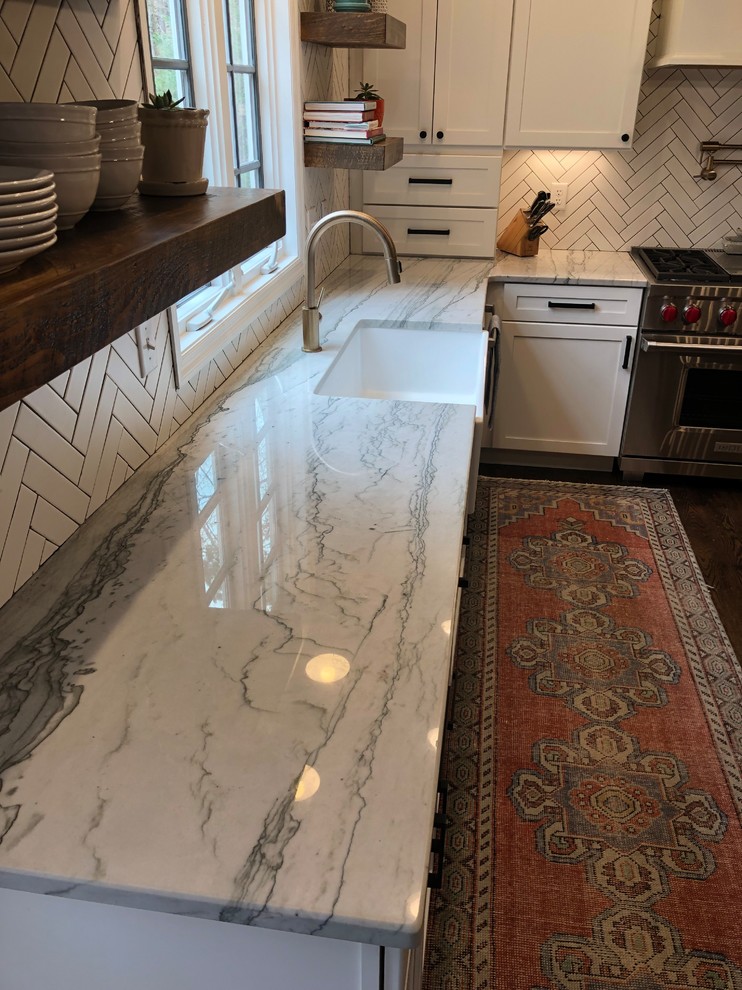 Large country u-shaped eat-in kitchen in Atlanta with a farmhouse sink, recessed-panel cabinets, white cabinets, quartz benchtops, white splashback, ceramic splashback, stainless steel appliances, dark hardwood floors, with island, brown floor and white benchtop.