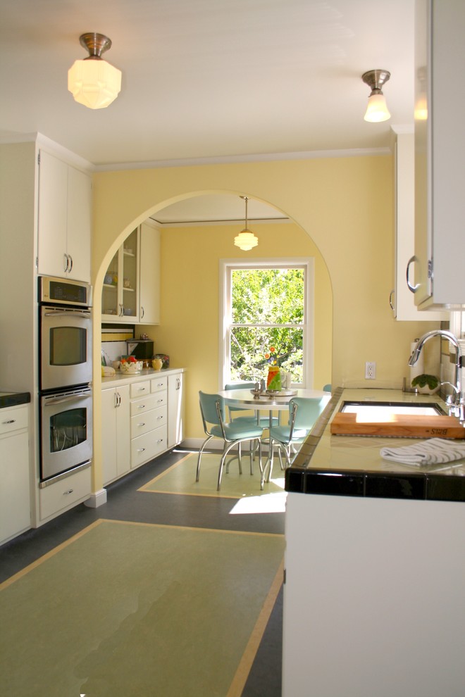 Mid-sized traditional galley separate kitchen in San Francisco with a single-bowl sink, flat-panel cabinets, white cabinets, tile benchtops, yellow splashback, ceramic splashback, stainless steel appliances, linoleum floors and no island.