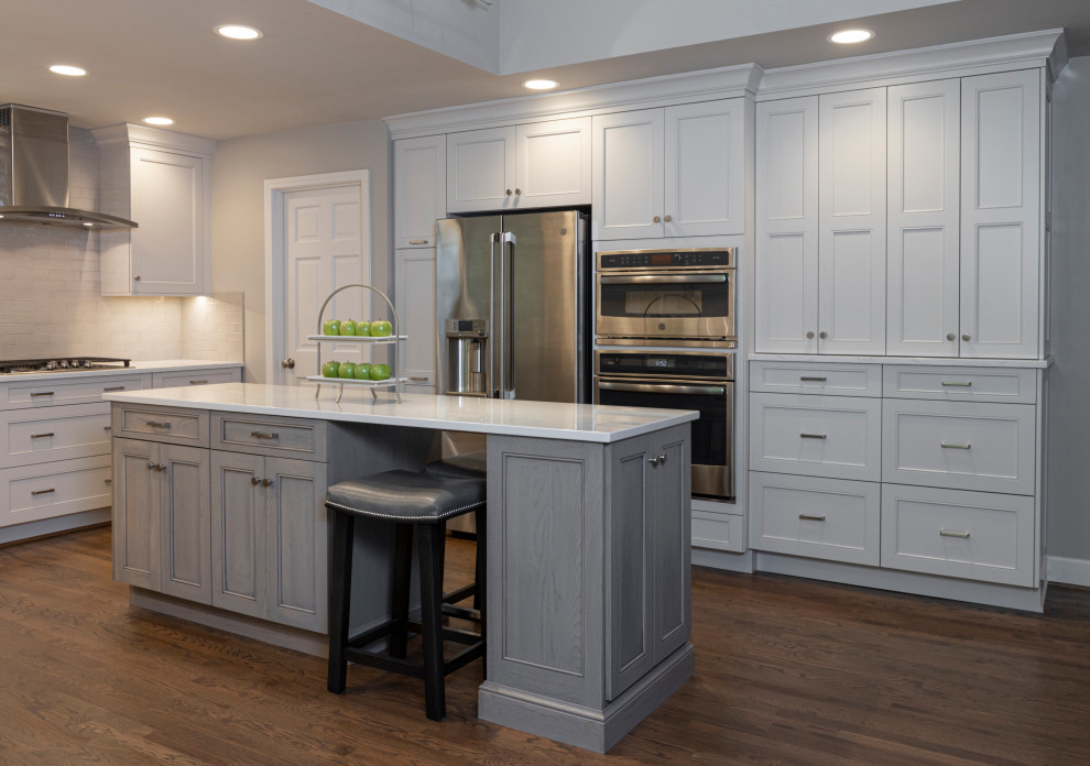 Inspiration for a large transitional u-shaped eat-in kitchen in Kansas City with an undermount sink, recessed-panel cabinets, grey cabinets, quartzite benchtops, white splashback, subway tile splashback, stainless steel appliances, medium hardwood floors, with island, brown floor and white benchtop.