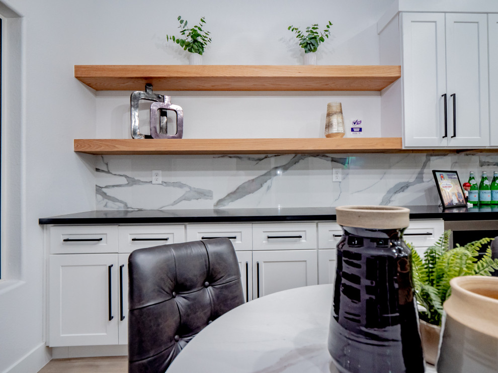 Idéer för ett stort modernt svart linjärt kök med öppen planlösning, med en undermonterad diskho, vita skåp, vitt stänkskydd, rostfria vitvaror, en köksö, brunt golv, skåp i shakerstil, bänkskiva i kvartsit, stänkskydd i keramik och vinylgolv