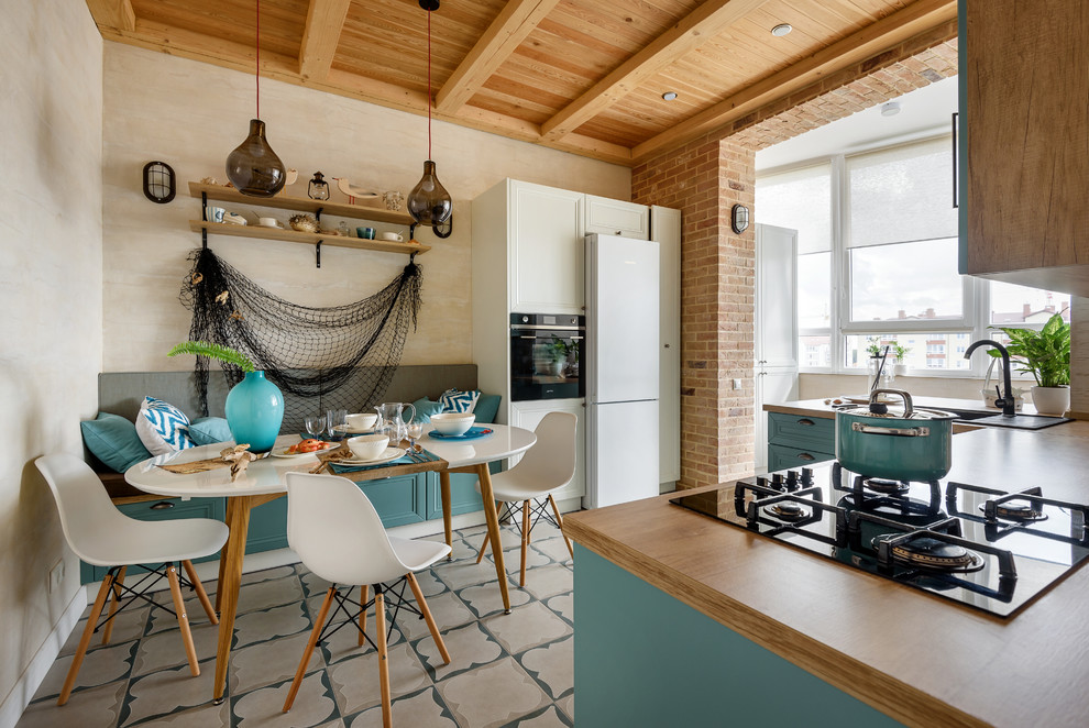 Design ideas for a beach style u-shaped eat-in kitchen in Other with a drop-in sink, recessed-panel cabinets, turquoise cabinets, wood benchtops, white appliances, a peninsula, multi-coloured floor and brown benchtop.