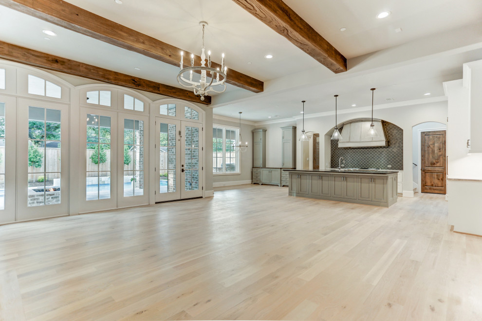 Design ideas for a large open plan games room in Houston with white walls, light hardwood flooring, a standard fireplace, a brick fireplace surround, beige floors and exposed beams.