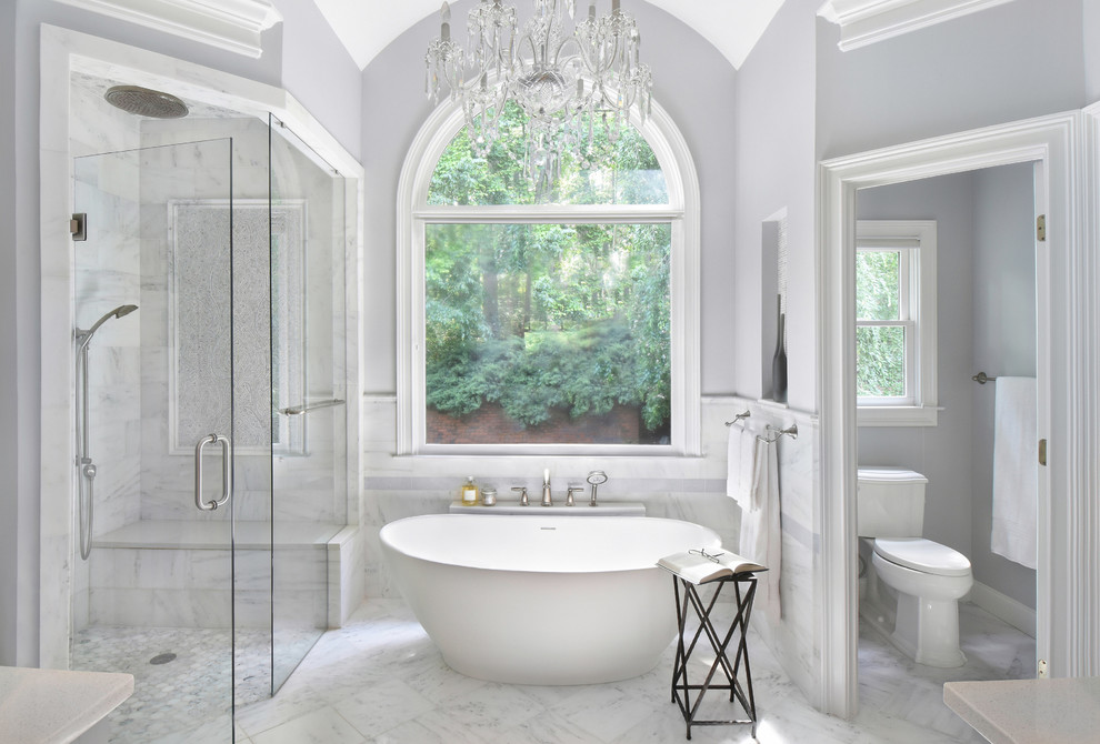 Inspiration for a transitional master bathroom in Atlanta with a freestanding tub, a curbless shower, a two-piece toilet, marble, marble floors, grey floor, a hinged shower door, white tile and grey walls.