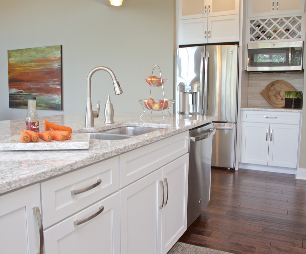 Mid-sized transitional galley dark wood floor eat-in kitchen photo with white cabinets, granite countertops, beige backsplash, stone tile backsplash, stainless steel appliances, a double-bowl sink, shaker cabinets and an island