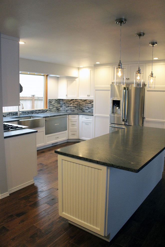 This is an example of a large arts and crafts u-shaped kitchen in Seattle with a farmhouse sink, white cabinets, soapstone benchtops, stainless steel appliances, with island, blue splashback, mosaic tile splashback and dark hardwood floors.