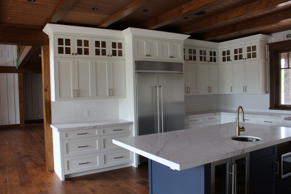 Inspiration for a large rustic u-shaped dark wood floor, brown floor and wood ceiling eat-in kitchen remodel in Toronto with a farmhouse sink, shaker cabinets, white cabinets, quartz countertops, white backsplash, subway tile backsplash, stainless steel appliances, an island and white countertops