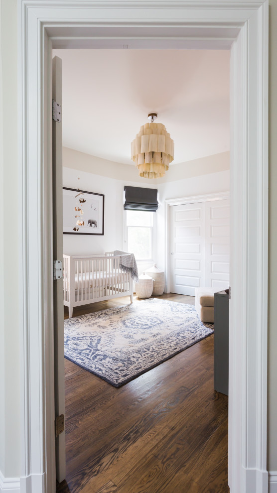 Cette image montre une chambre de bébé neutre traditionnelle avec un mur blanc, un sol en bois brun, un sol marron et un plafond en papier peint.