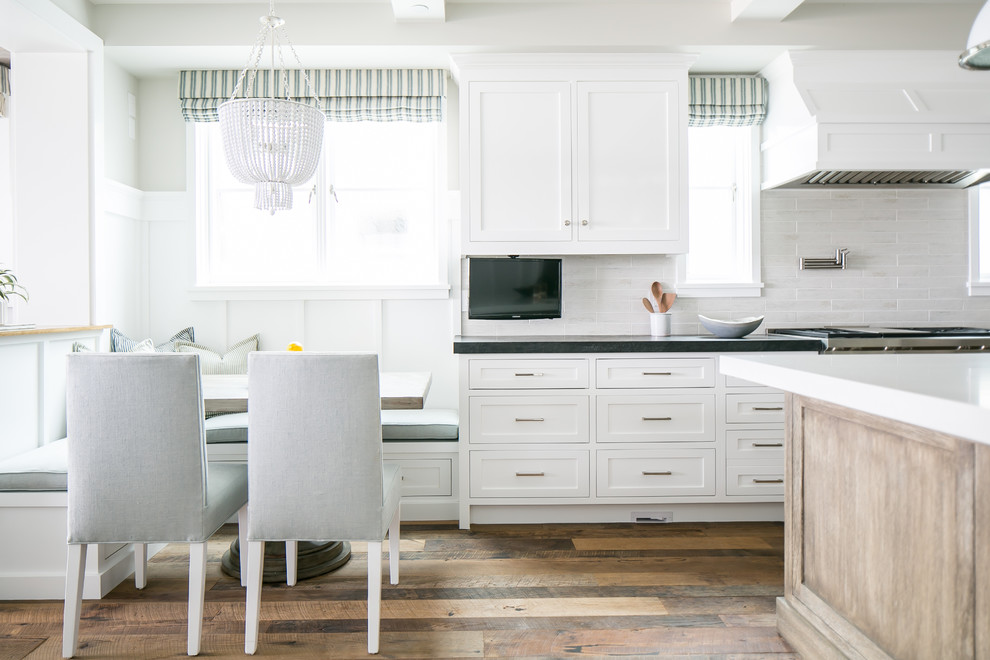 Inspiration for a beach style eat-in kitchen in Orange County with shaker cabinets, white cabinets, white splashback, with island and dark hardwood floors.