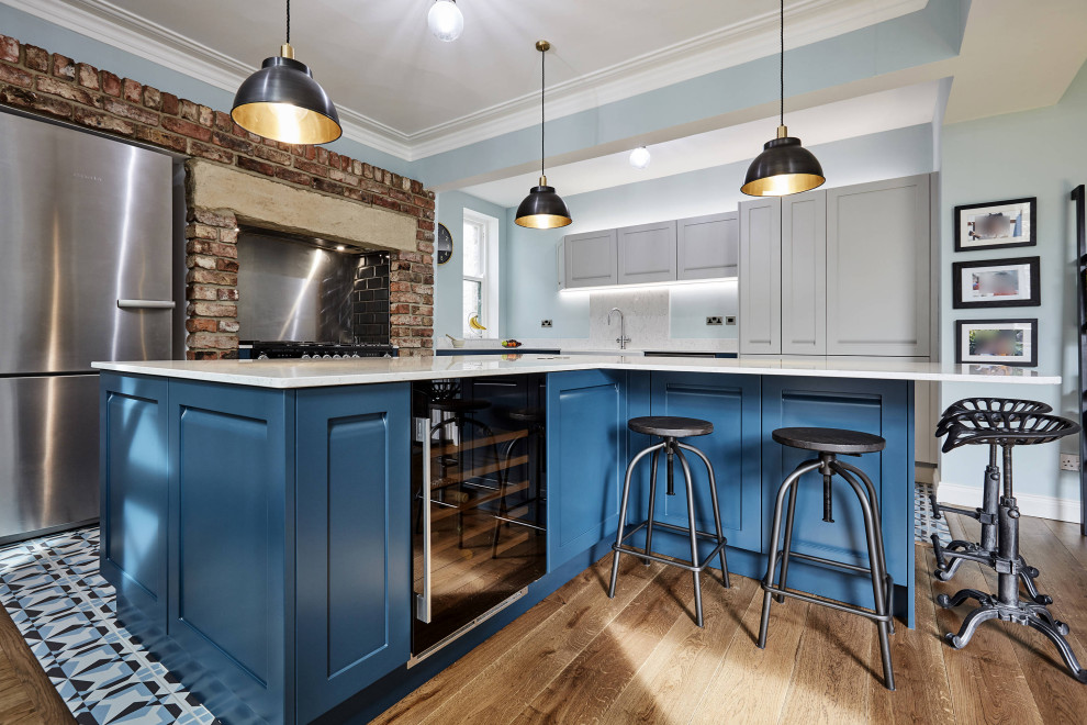 Photo of a large transitional l-shaped eat-in kitchen in Other with a farmhouse sink, shaker cabinets, blue cabinets, marble benchtops, white splashback, marble splashback, stainless steel appliances, porcelain floors, multiple islands, blue floor, white benchtop and coffered.