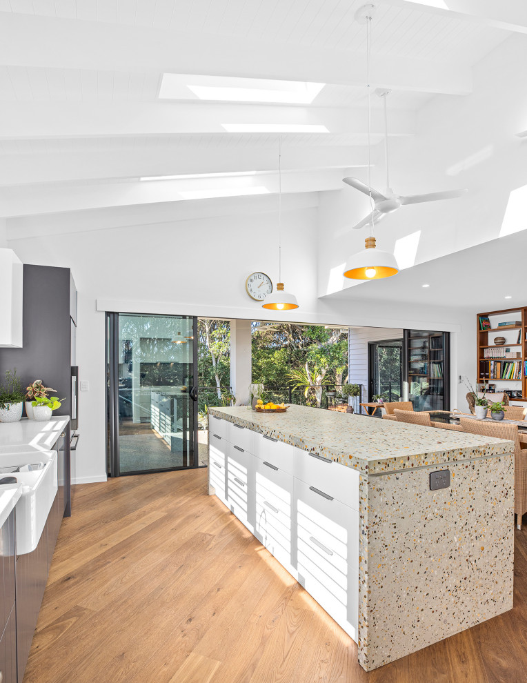 Design ideas for a large galley kitchen pantry in Other with a farmhouse sink, concrete benchtops, metallic splashback, porcelain splashback, black appliances, medium hardwood floors, with island and exposed beam.