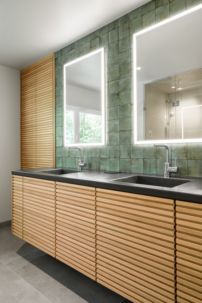 Свежая идея для дизайна: главная ванная комната с светлыми деревянными фасадами, зеленой плиткой, полом из керамогранита, монолитной раковиной, столешницей из бетона, серым полом, душем с распашными дверями, серой столешницей, сиденьем для душа, тумбой под две раковины и подвесной тумбой - отличное фото интерьера