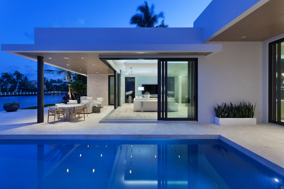 Design ideas for a large modern backyard patio in Miami with concrete slab and a roof extension.
