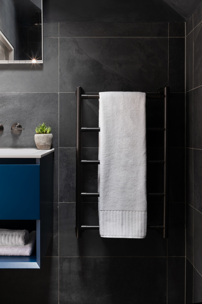 Photo of a small modern 3/4 wet room bathroom in London with flat-panel cabinets, blue cabinets, a wall-mount toilet, black tile, porcelain tile, a drop-in sink, solid surface benchtops, black floor, an open shower, white benchtops, a single vanity and a freestanding vanity.
