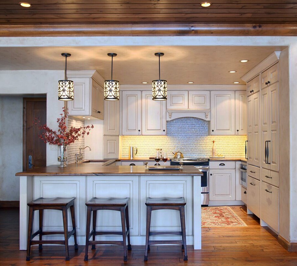 Design ideas for a small traditional l-shaped open plan kitchen in Denver with a drop-in sink, raised-panel cabinets, beige cabinets, wood benchtops, beige splashback, mosaic tile splashback, stainless steel appliances, medium hardwood floors and no island.