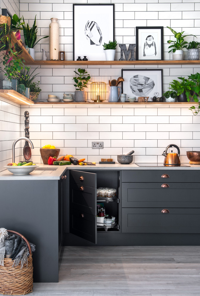 Design ideas for a medium sized traditional u-shaped open plan kitchen in Cornwall with a built-in sink, shaker cabinets, grey cabinets, concrete worktops, white splashback, glass tiled splashback, black appliances, laminate floors, no island and white worktops.