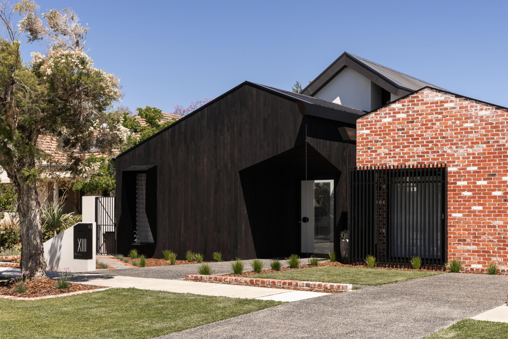 Foto på ett mellanstort funkis svart hus, med allt i ett plan, sadeltak och tak i metall