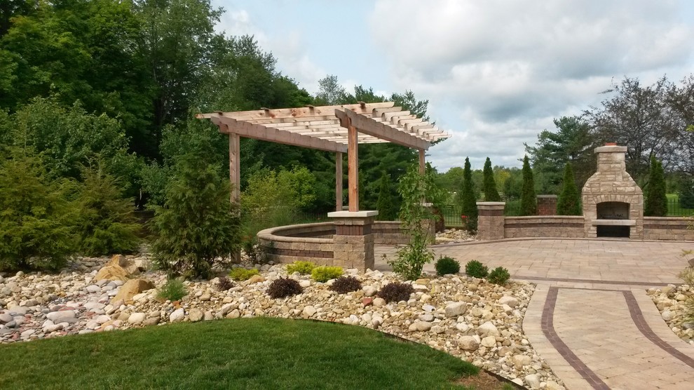 This is an example of a large transitional backyard patio in Columbus with a fire feature, concrete pavers and a pergola.