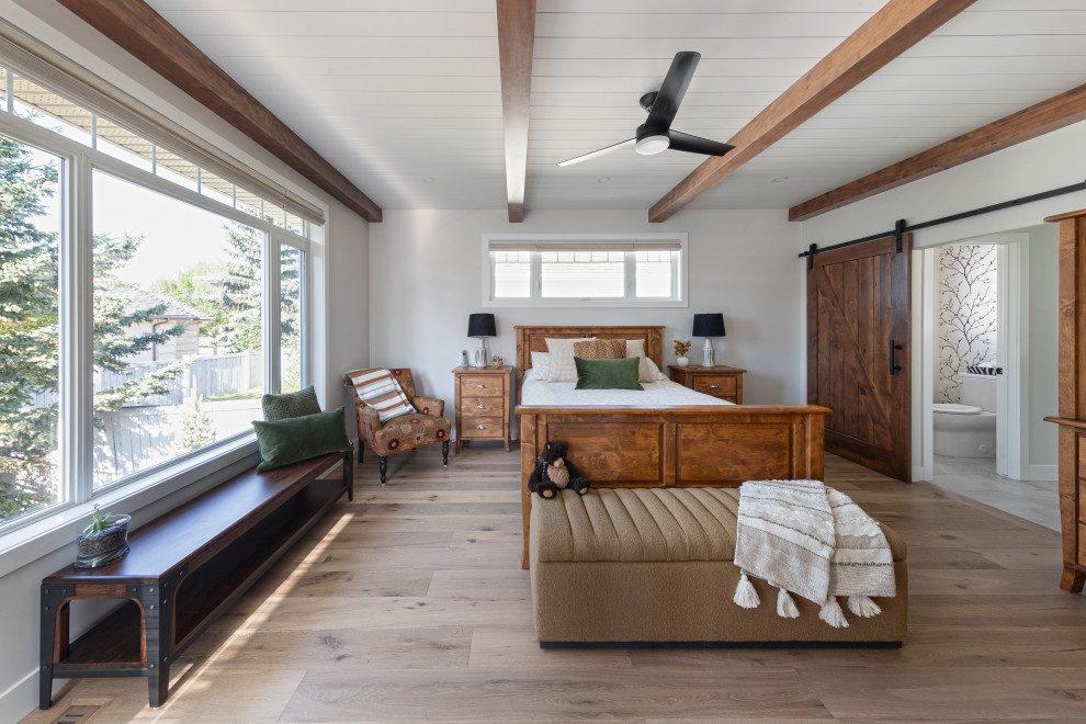 Ejemplo de dormitorio principal campestre de tamaño medio con paredes blancas, suelo vinílico, suelo marrón y machihembrado