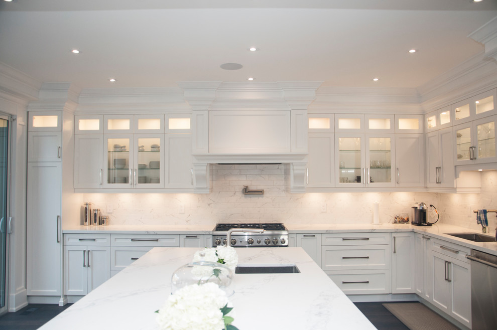 Enclosed kitchen - large transitional l-shaped dark wood floor and brown floor enclosed kitchen idea in Toronto with an undermount sink, shaker cabinets, white cabinets, quartz countertops, white backsplash, marble backsplash, stainless steel appliances, an island and white countertops