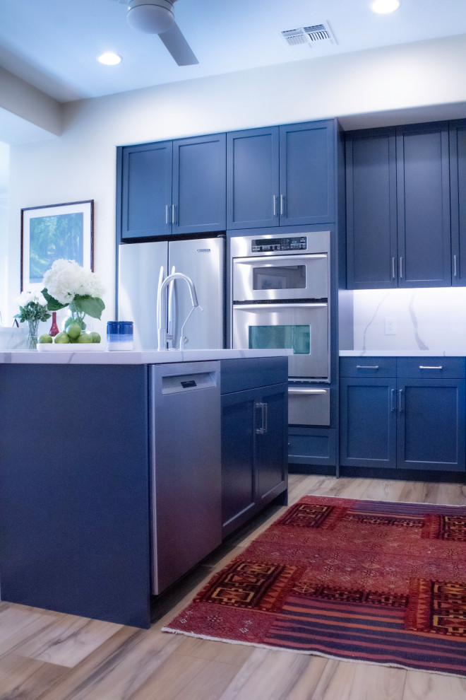 Eat-in kitchen - mid-sized transitional eat-in kitchen idea in Phoenix with an undermount sink, shaker cabinets, blue cabinets, quartz countertops, white backsplash, quartz backsplash, stainless steel appliances, an island and white countertops
