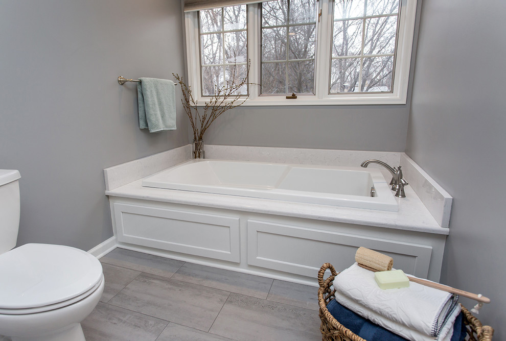 Inspiration for a mid-sized transitional master bathroom in Other with recessed-panel cabinets, white cabinets, a drop-in tub, an open shower, a two-piece toilet, grey walls, ceramic floors, an undermount sink, engineered quartz benchtops, grey floor, an open shower and white benchtops.