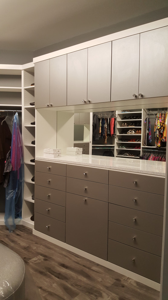 This is an example of a large modern gender-neutral walk-in wardrobe with flat-panel cabinets, grey cabinets, vinyl floors and brown floor.