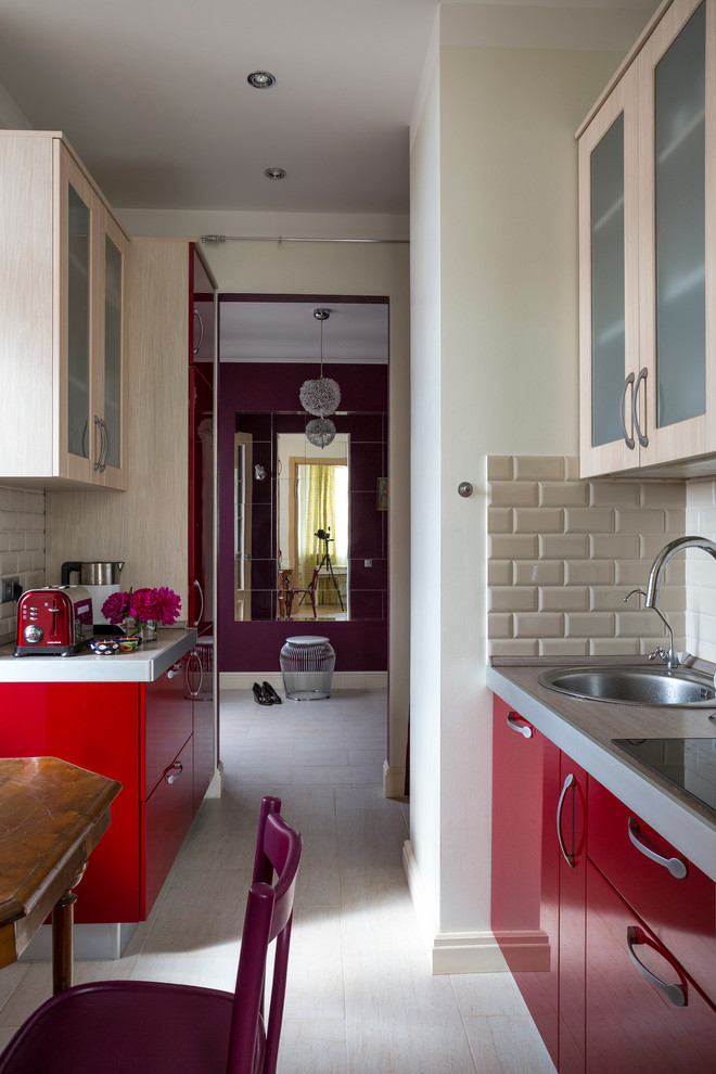 This is an example of a small contemporary galley separate kitchen in Moscow with flat-panel cabinets, red cabinets, solid surface benchtops, beige splashback, panelled appliances, porcelain floors, a drop-in sink, subway tile splashback, no island and white floor.