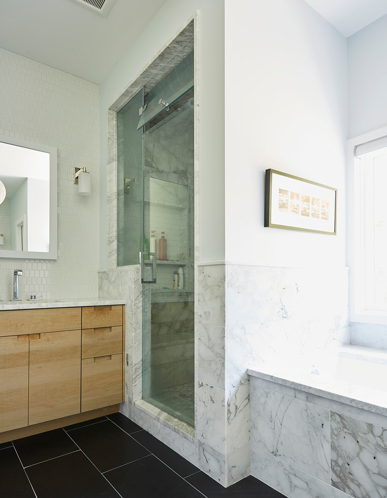 This is an example of a mid-sized contemporary master bathroom in Richmond with flat-panel cabinets, light wood cabinets, an undermount tub, an alcove shower, gray tile, marble, white walls, porcelain floors, an undermount sink, marble benchtops, black floor and a hinged shower door.