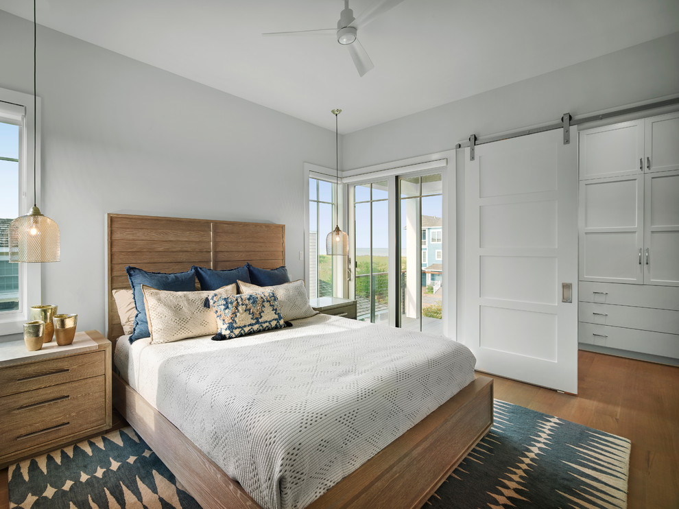 Example of a large beach style master medium tone wood floor and brown floor bedroom design with gray walls and no fireplace