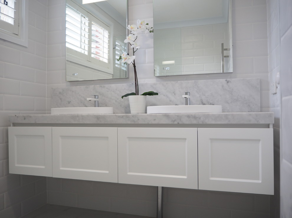 Inspiration for a mid-sized contemporary master bathroom in Sydney with shaker cabinets, white cabinets, a corner shower, white tile, subway tile, white walls, marble floors, an integrated sink, marble benchtops and a hinged shower door.