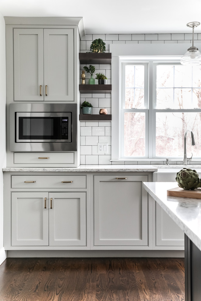 Transitional l-shaped medium tone wood floor and brown floor eat-in kitchen photo in Boston with a farmhouse sink, beaded inset cabinets, white cabinets, quartz countertops, white backsplash, subway tile backsplash, stainless steel appliances, an island and gray countertops
