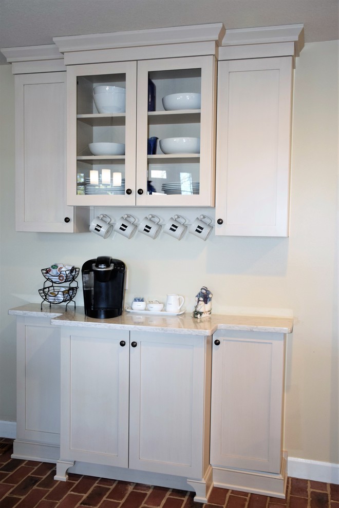 Example of a mid-sized transitional u-shaped brick floor eat-in kitchen design with a farmhouse sink, shaker cabinets, white cabinets, quartzite countertops, white backsplash, subway tile backsplash, stainless steel appliances and an island