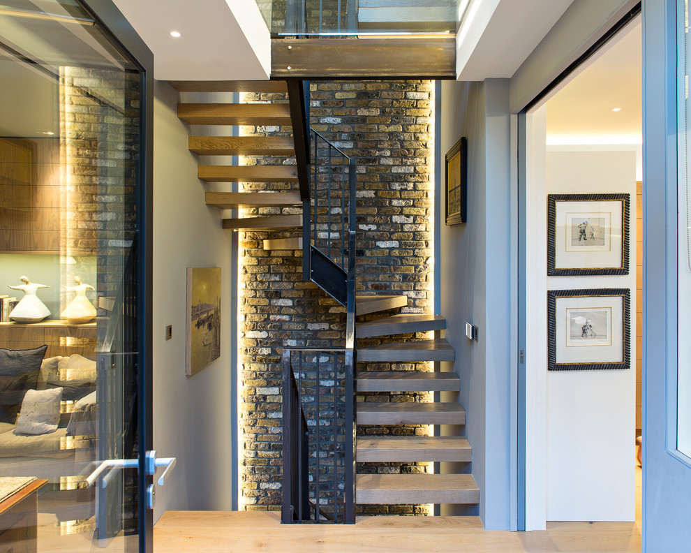 Design ideas for a contemporary wood u-shaped staircase in London with open risers and metal railing.