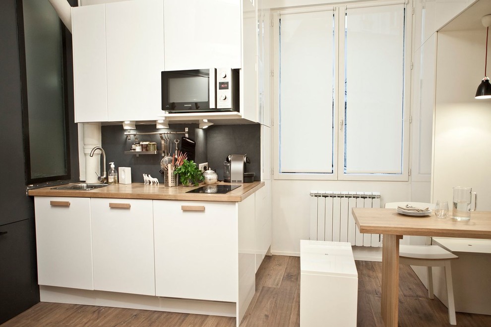 This is an example of a mid-sized contemporary single-wall eat-in kitchen in Paris with white cabinets, medium hardwood floors and no island.
