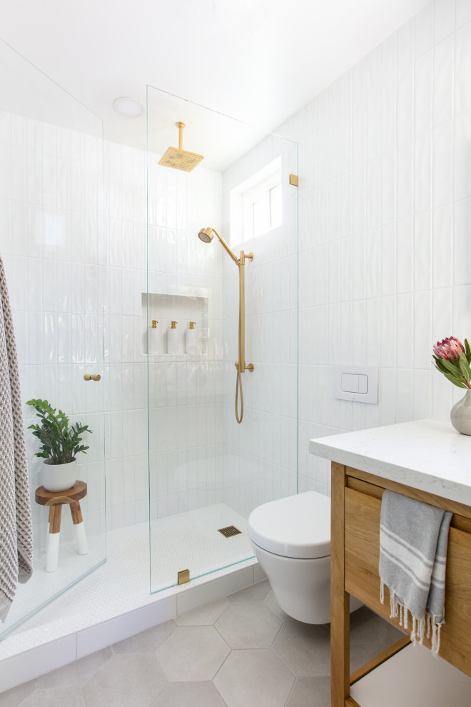 Exemple d'une salle de bain blanche et bois moderne en bois clair de taille moyenne avec un mur bleu, un sol gris, une douche double, WC suspendus, un carrelage blanc, des carreaux de céramique, un sol en carrelage de porcelaine, un plan de toilette en quartz modifié, une cabine de douche à porte battante, un plan de toilette blanc, meuble simple vasque et meuble-lavabo sur pied.