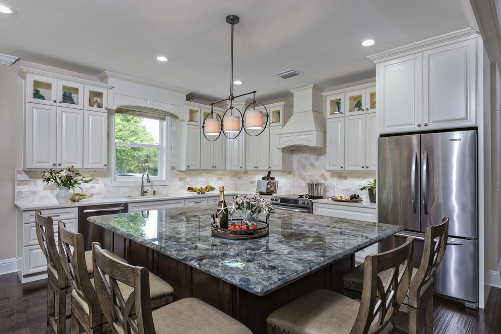 This is an example of a traditional l-shaped eat-in kitchen in Miami with a single-bowl sink, raised-panel cabinets, beige cabinets, granite benchtops, beige splashback, subway tile splashback, stainless steel appliances, dark hardwood floors and with island.
