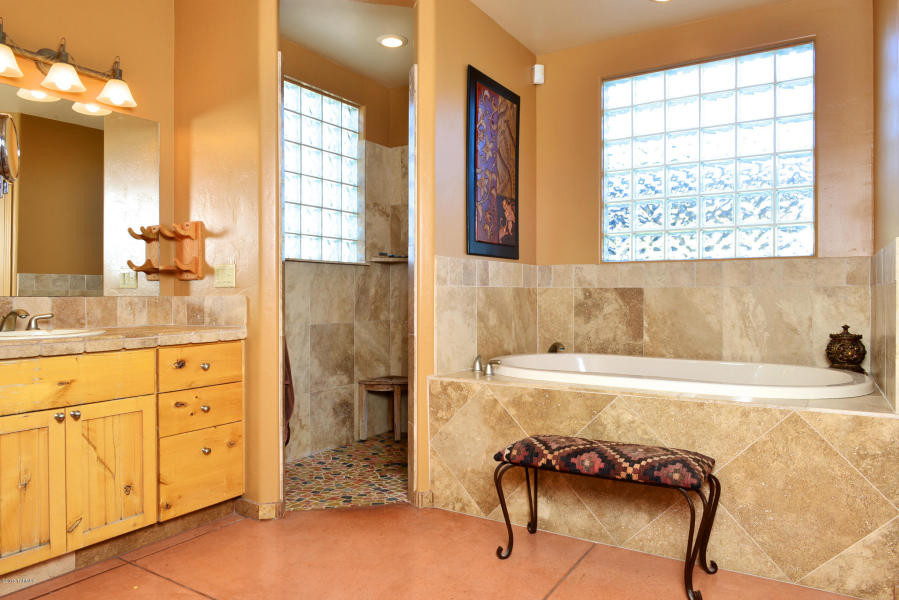 Design ideas for a large master bathroom in Phoenix with recessed-panel cabinets, light wood cabinets, a drop-in tub, an open shower, brown tile, travertine, brown walls, concrete floors, a drop-in sink, tile benchtops, orange floor and an open shower.