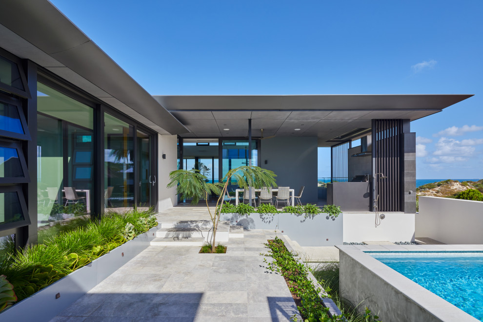 Photo of a large contemporary side yard rectangular aboveground pool in Perth with a pool house and concrete pavers.