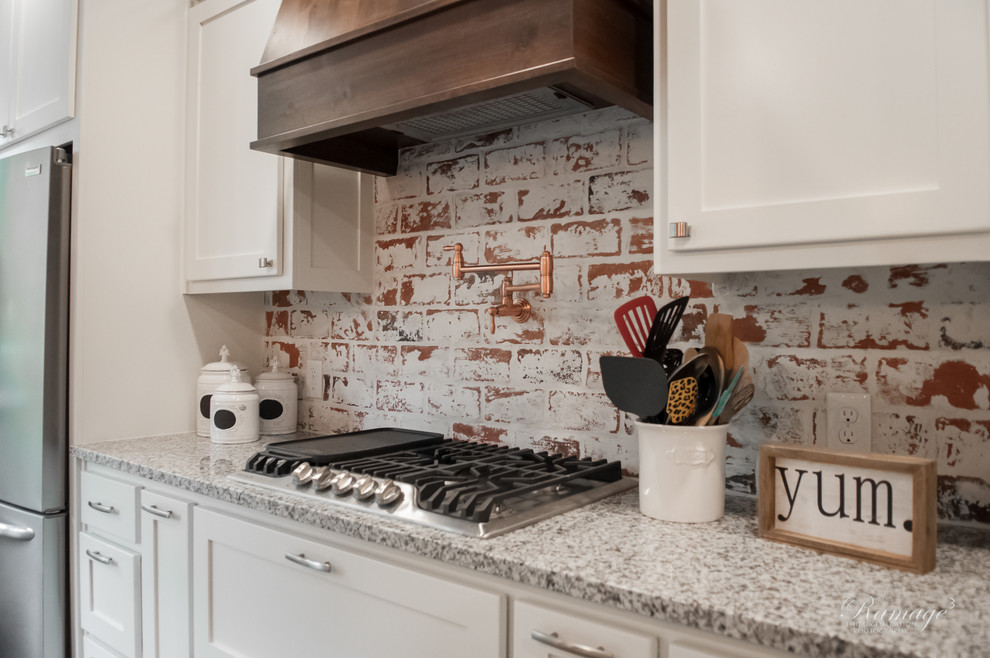 Open concept kitchen - large transitional u-shaped porcelain tile and brown floor open concept kitchen idea with a farmhouse sink, shaker cabinets, white cabinets, granite countertops, multicolored backsplash, brick backsplash, stainless steel appliances, an island and gray countertops