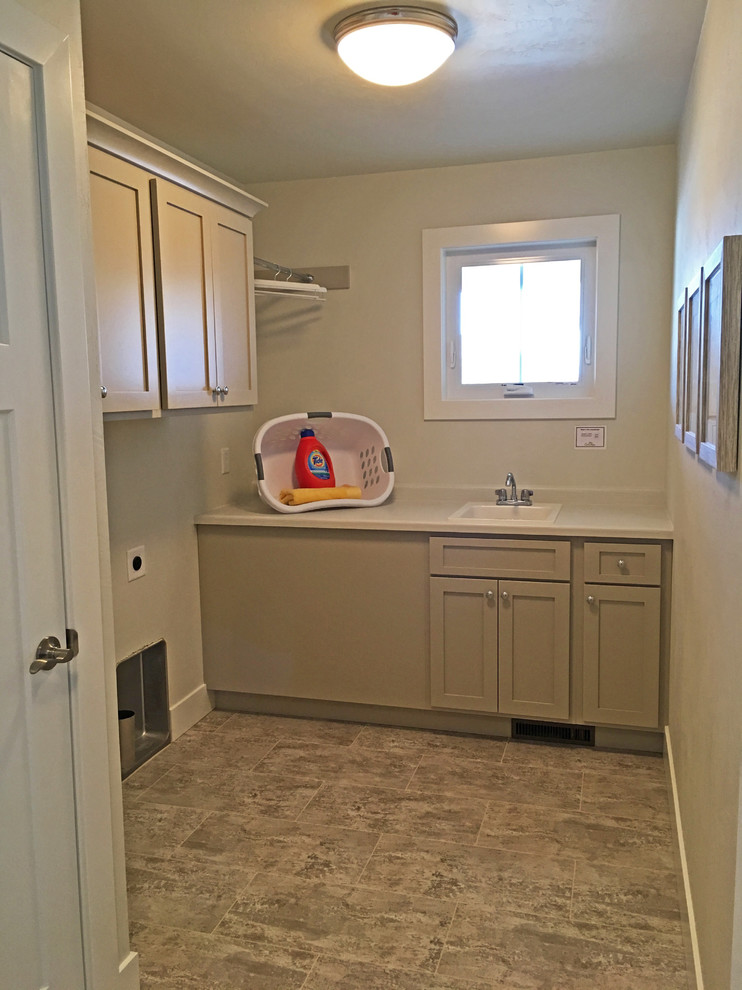 This is an example of a large arts and crafts l-shaped dedicated laundry room in Other with a drop-in sink, shaker cabinets, beige cabinets, solid surface benchtops, beige walls, ceramic floors, a side-by-side washer and dryer and beige benchtop.
