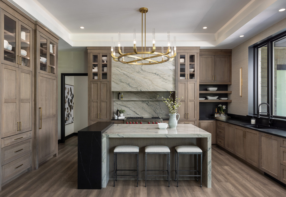 Open concept kitchen - large farmhouse u-shaped medium tone wood floor, brown floor and tray ceiling open concept kitchen idea in Detroit with an undermount sink, flat-panel cabinets, medium tone wood cabinets, quartzite countertops, gray backsplash, quartz backsplash, paneled appliances, an island and gray countertops