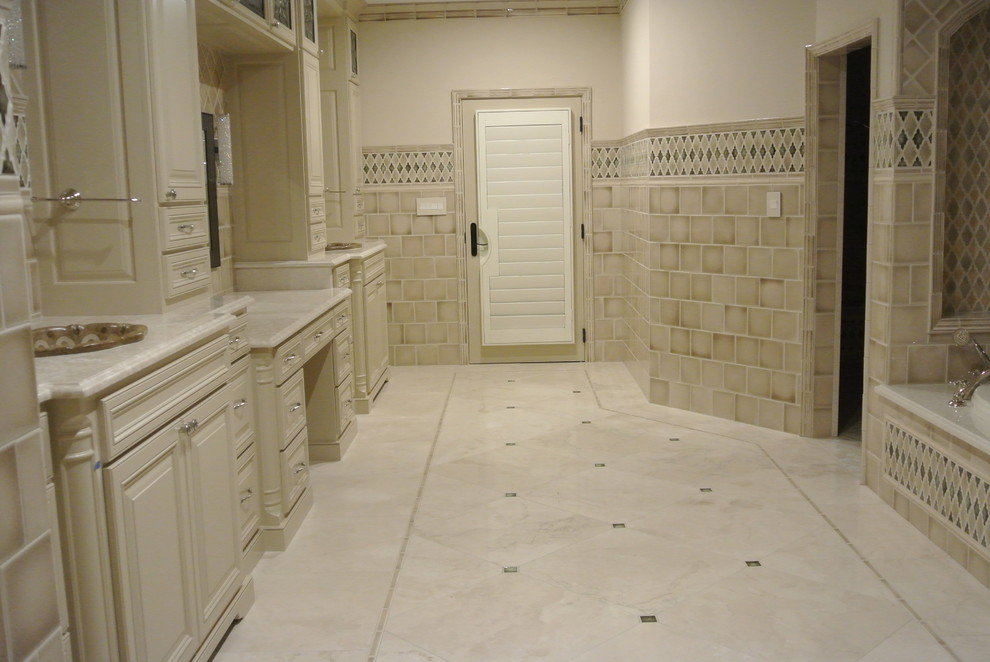 This is an example of a large transitional master bathroom in Dallas with a drop-in sink, furniture-like cabinets, beige cabinets, granite benchtops, a drop-in tub, a curbless shower, a one-piece toilet, beige tile, beige walls and marble floors.