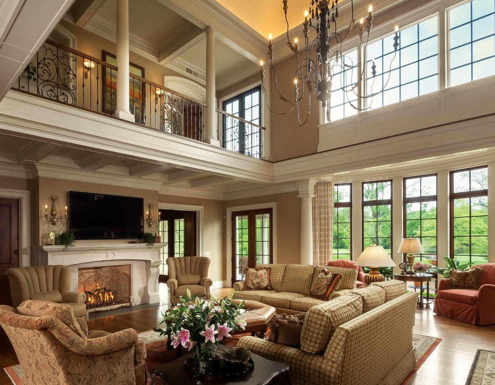 Expansive mediterranean open concept living room in Columbus with beige walls, medium hardwood floors, a standard fireplace, a stone fireplace surround, a wall-mounted tv and brown floor.