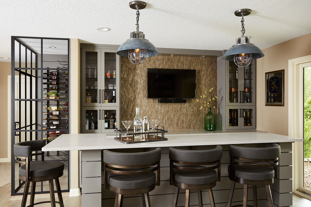 Design ideas for a mid-sized transitional seated home bar in Minneapolis with grey cabinets, quartzite benchtops, light hardwood floors, glass-front cabinets, beige splashback and beige floor.