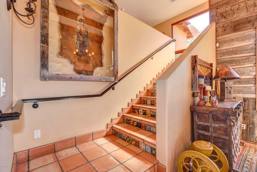 Large terracotta l-shaped staircase in Phoenix with terracotta risers and metal railing.