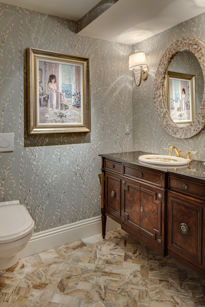 Inspiration for a mid-sized traditional powder room in Miami with furniture-like cabinets, dark wood cabinets, a wall-mount toilet, marble floors, a drop-in sink, granite benchtops, grey walls and multi-coloured floor.