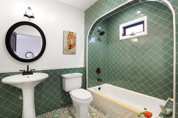 Photo of a mid-sized bathroom in Los Angeles with a pedestal sink, raised-panel cabinets, white cabinets, marble benchtops, a corner tub, a shower/bathtub combo, a two-piece toilet, green tile, ceramic tile, white walls and ceramic floors.
