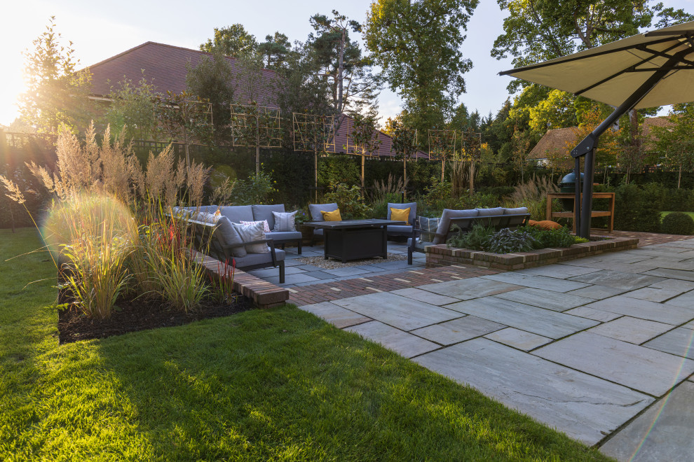 Large contemporary backyard patio in Buckinghamshire with a fire feature and brick pavers.