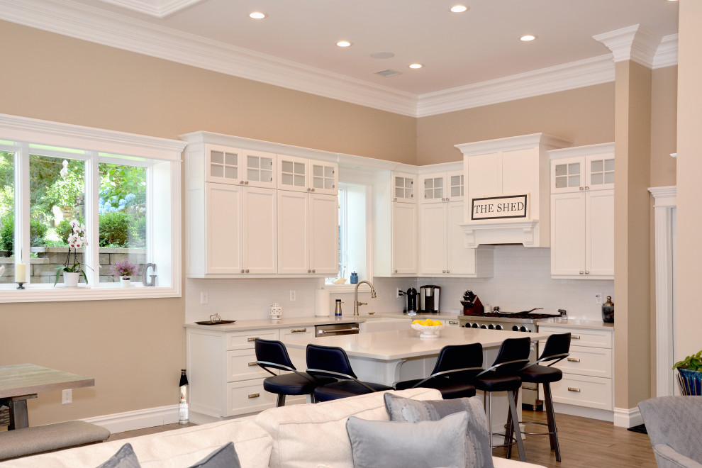 Open concept kitchen - mid-sized transitional l-shaped porcelain tile and beige floor open concept kitchen idea in New York with a farmhouse sink, shaker cabinets, white cabinets, granite countertops, white backsplash, subway tile backsplash, stainless steel appliances, an island and white countertops