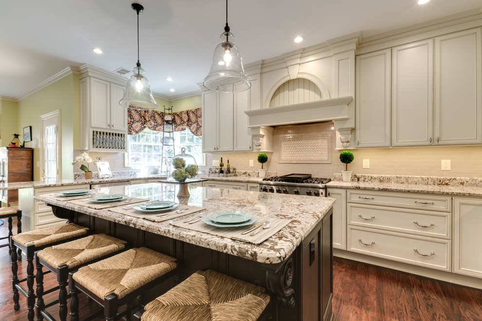 Photo of a large transitional u-shaped eat-in kitchen in Atlanta with a single-bowl sink, recessed-panel cabinets, white cabinets, granite benchtops, beige splashback, porcelain splashback, stainless steel appliances, dark hardwood floors and with island.